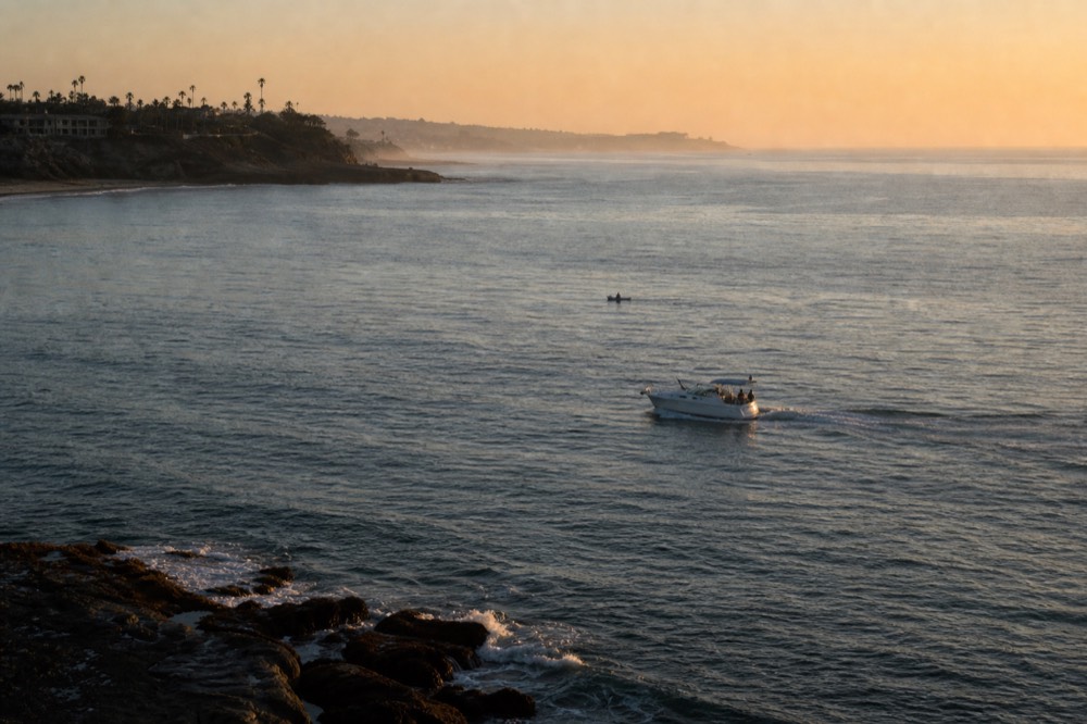 Open Pacific water and a hazy coastline stretching south from San Diego at golden hour, long shadows and warm low light