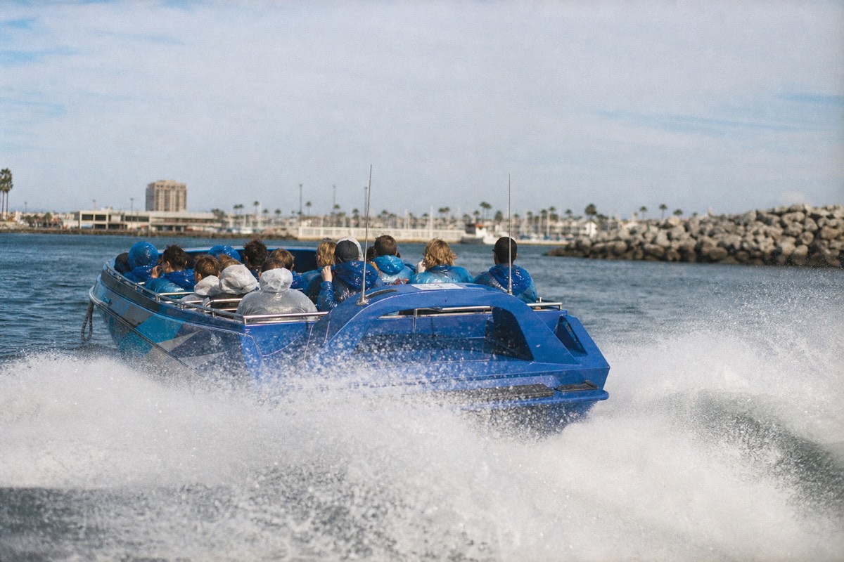Open jet boat at speed on San Diego Bay throwing spray, downtown skyline in the background
