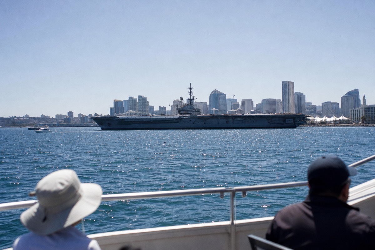 Passengers at the rail of an open-deck sightseeing boat on San Diego Bay with the downtown skyline behind them