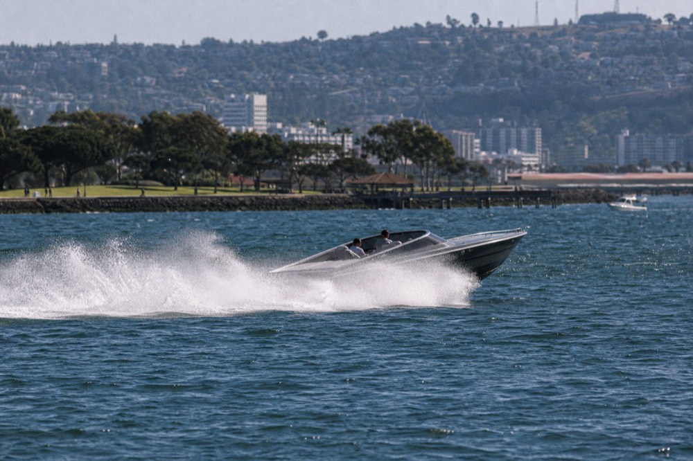 A fast open jet boat throwing spray on San Diego Bay, late-morning light