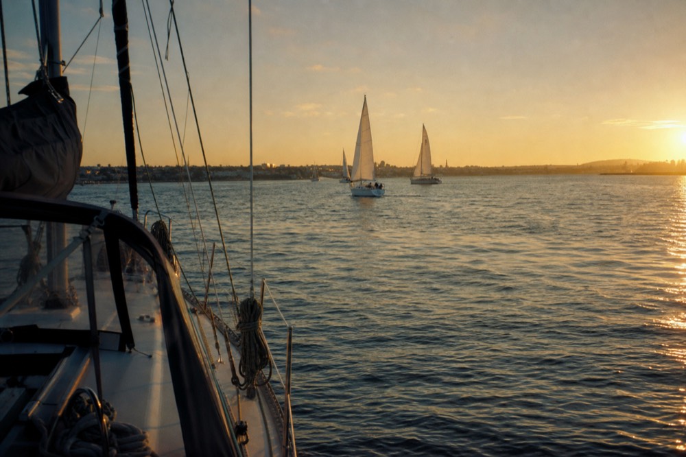 Sunset light over San Diego Bay and its sailboats at golden hour, long shadows and warm low light